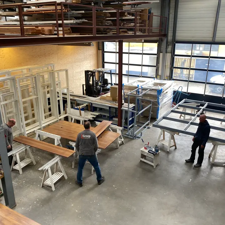Medewerkers van L-Groep bouwbedrijf aan het werk in de werkplaats met hout en kozijnen voor totaalonderhoud in Den Haag.